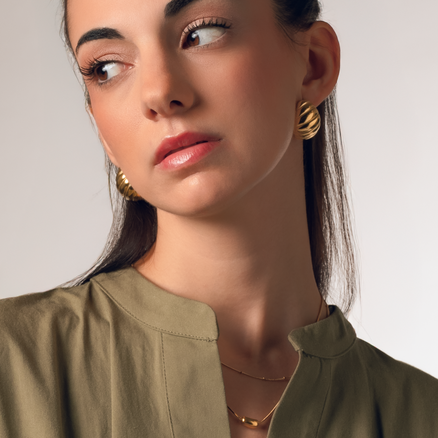 Pendientes Cruasán Gold en baño de oro usados en modelo, ideales para looks modernos y sofisticados.