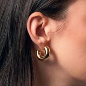 Pendientes Maca Gold de aro grueso en baño de oro usados en modelo, ideales para looks llamativos y sofisticados.