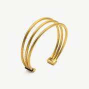 Pulsera Trinity Gold trenzada en color dorado, diseño de tres bandas entrelazadas, elegante de Manía de Manía.